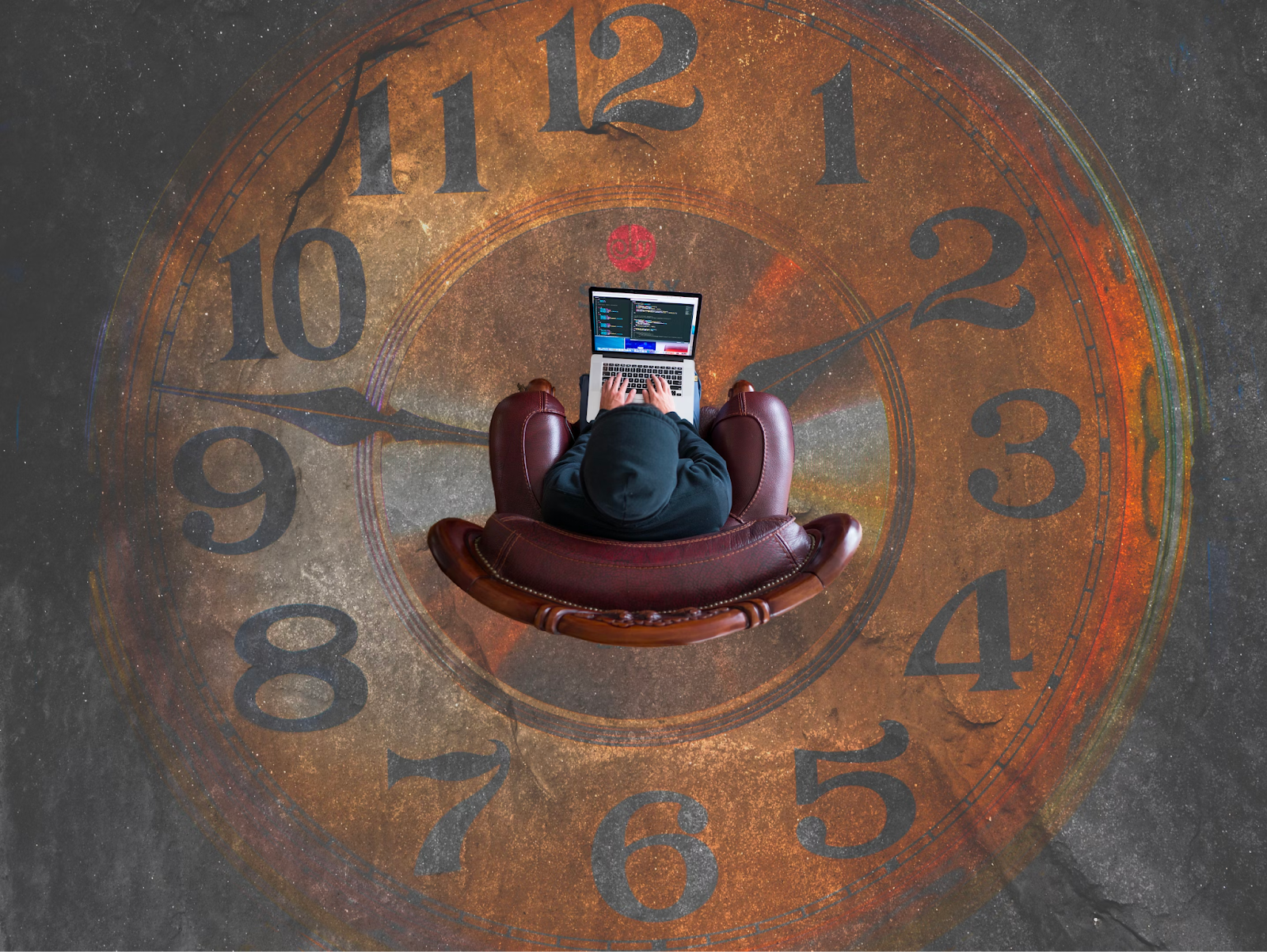 Person using the computer sitting in a chair placed on a clock floor